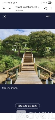 A wooden staircase surrounded by greenery leading to a property.