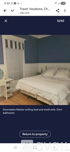 A bedroom with a white bed and a window with blinds.