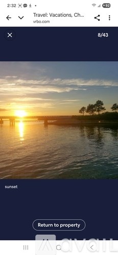 A sunset over a body of water with trees in the background.