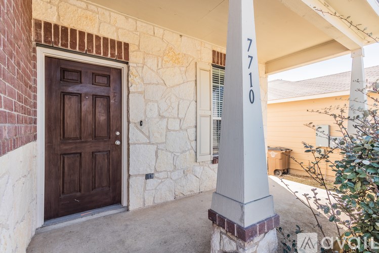 A house numbered 7710 is shown with a brown door and a stone wall.