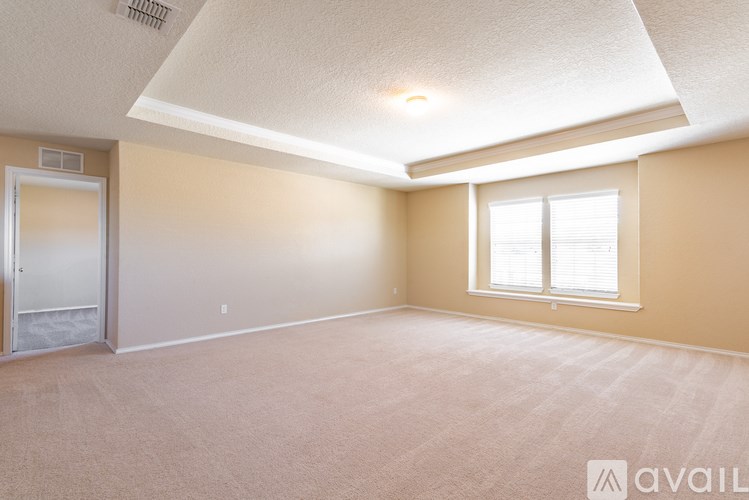 A room with a carpeted floor, a door, and a window.