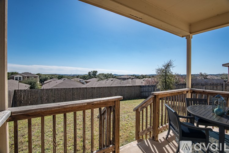 A wooden deck with a table and chairs overlooks a residential area.