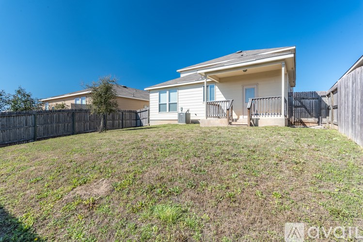 A house with a fence and a lawn in front of it.