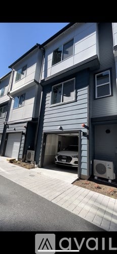 A modern two-story building with a garage and a car inside.