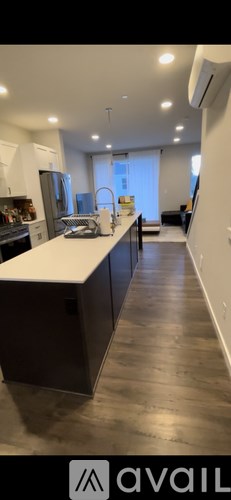 A modern kitchen with dark wood floors and white countertops.