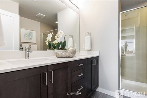 A bathroom with a white sink and brown cabinets.