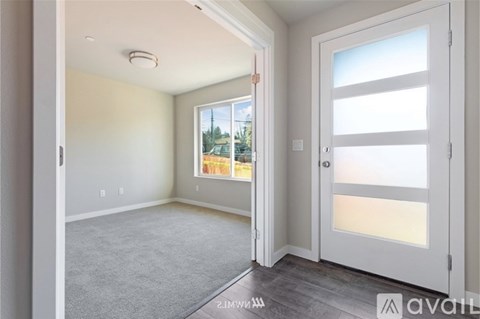 A room with a carpeted floor, a door, and a window showing a view of trees and a house.