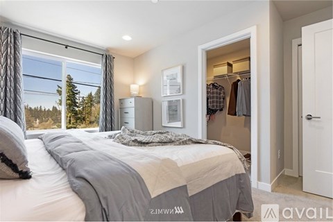 A bedroom with a large bed and a view of trees outside the window.
