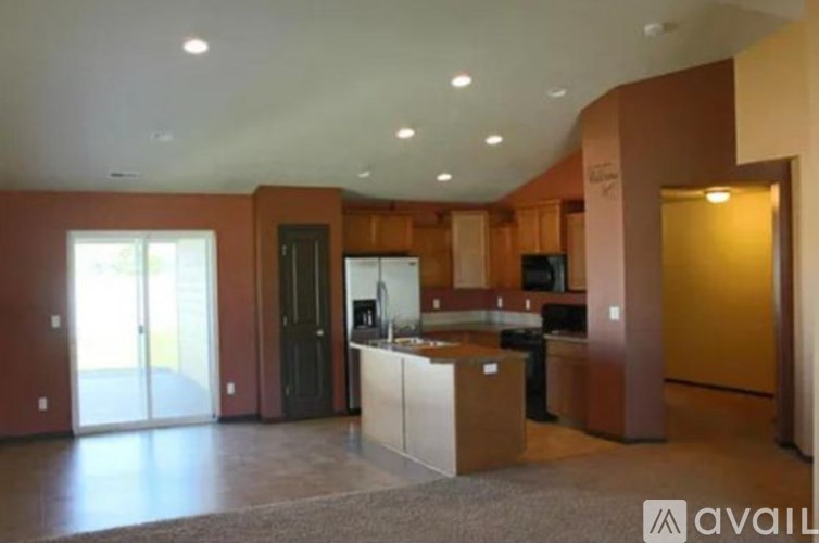 A spacious living room with a kitchen area in the background.
