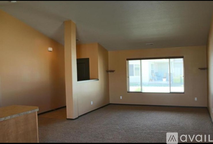 A room with a carpeted floor and a window with a view of a street.