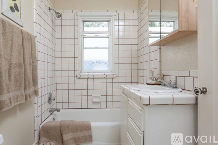 A bathroom with a white tiled wall and a window.