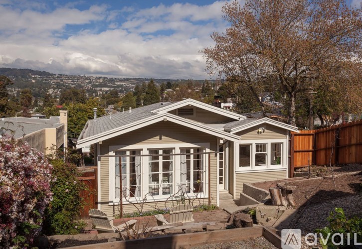 A house with a grey roof and white windows is surrounded by a garden.
