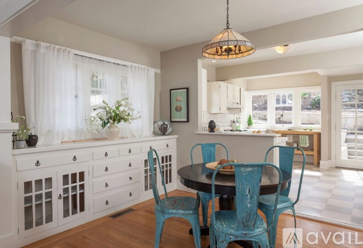 A dining room with a table set for two and a chandelier hanging from the ceiling.