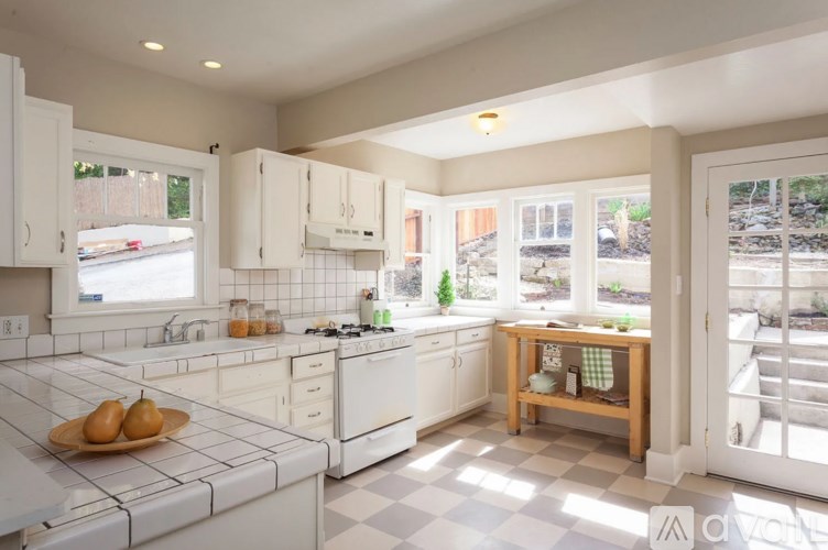 A kitchen with white cabinets and a checkered floor.
