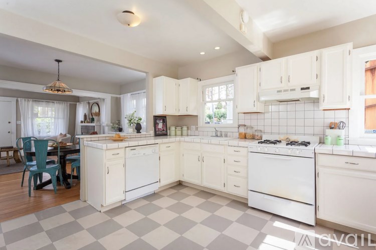 A kitchen with white cabinets and a checkered floor.