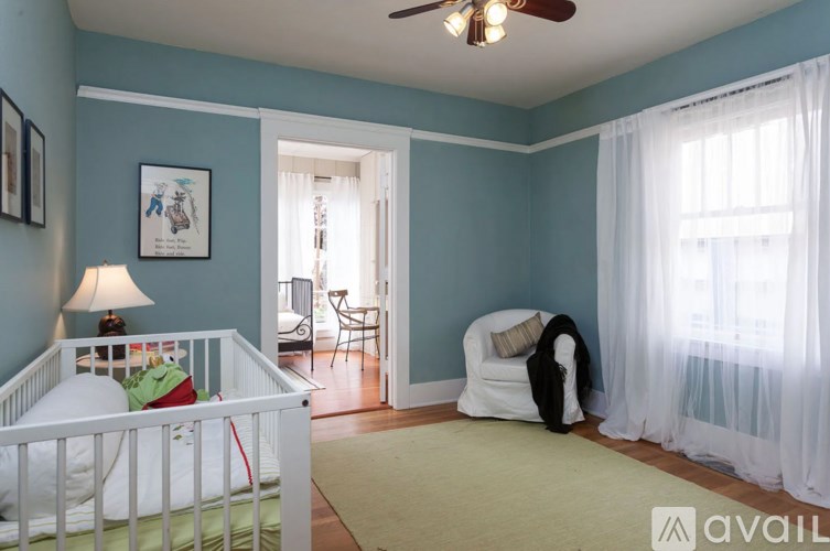 A baby's room with a white crib and a ceiling fan.