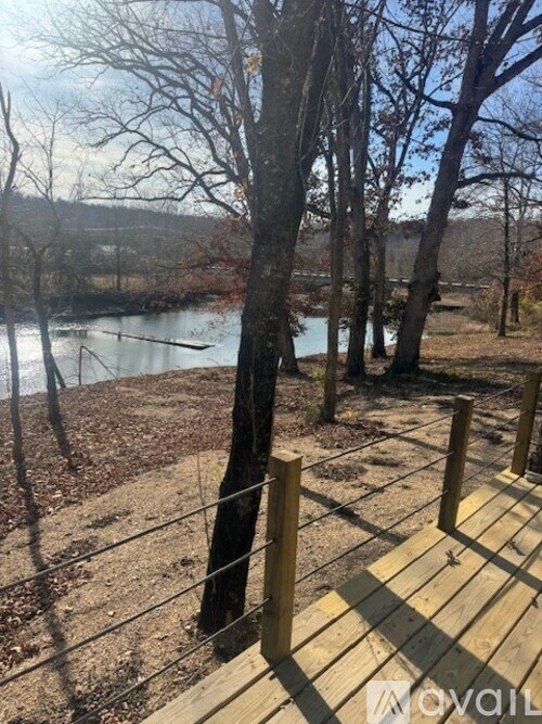 A wooden deck overlooks a river with trees on the left.