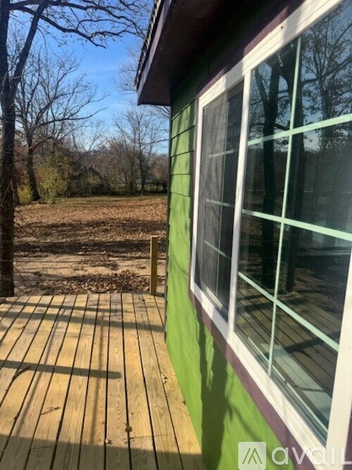 A green house with a wooden deck and a window.