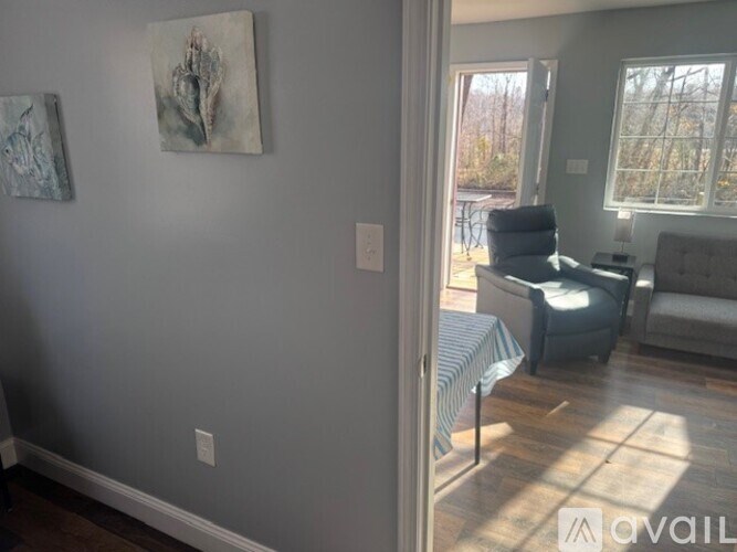 A living room with a grey couch and a painting on the wall.