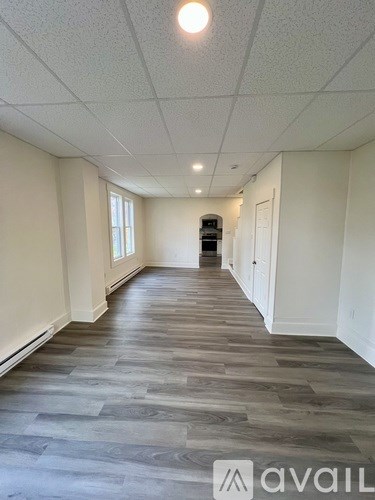A long hallway with wood flooring and white walls.