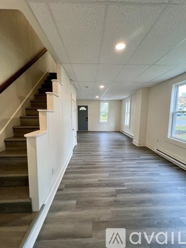 A hallway with a staircase and a door at the end.