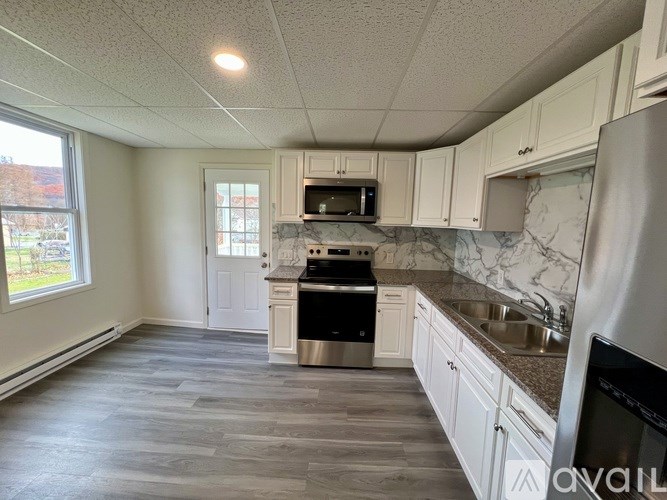 A kitchen with white cabinets and a marble backsplash.