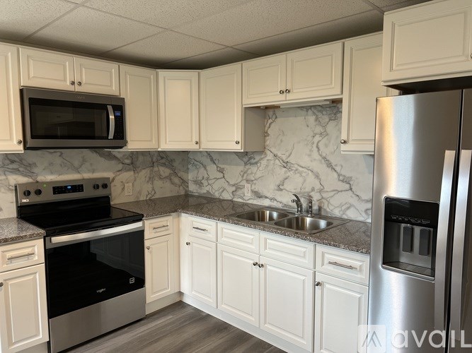 A kitchen with white cabinets and a marble backsplash.