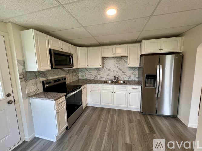 A kitchen with white cabinets and a marble backsplash.