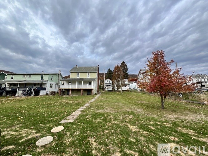 A grassy field with a tree and a path leading to a building.
