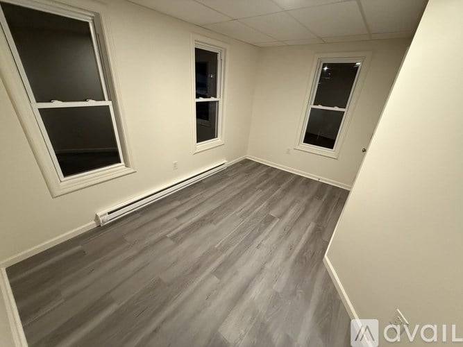 A room with a grey floor and three windows.