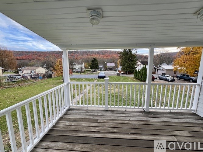 A porch with a view of a neighborhood and trees.