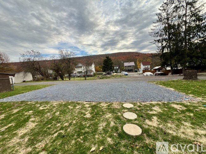 A backyard with a blue gravel area and a grassy area with stepping stones.