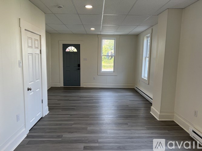 A room with a wooden floor and a black door.