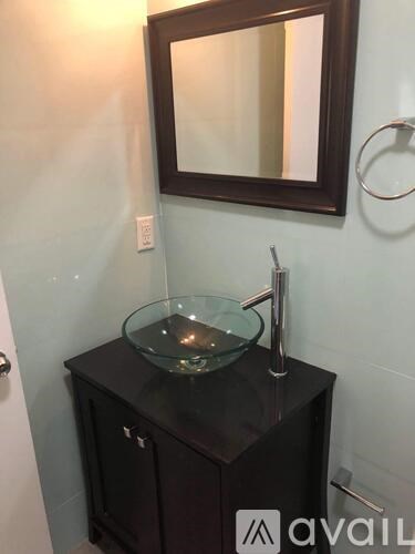 A bathroom vanity with a mirror and a glass bowl sink.