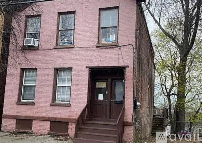 A red brick building with a brown front door and steps.