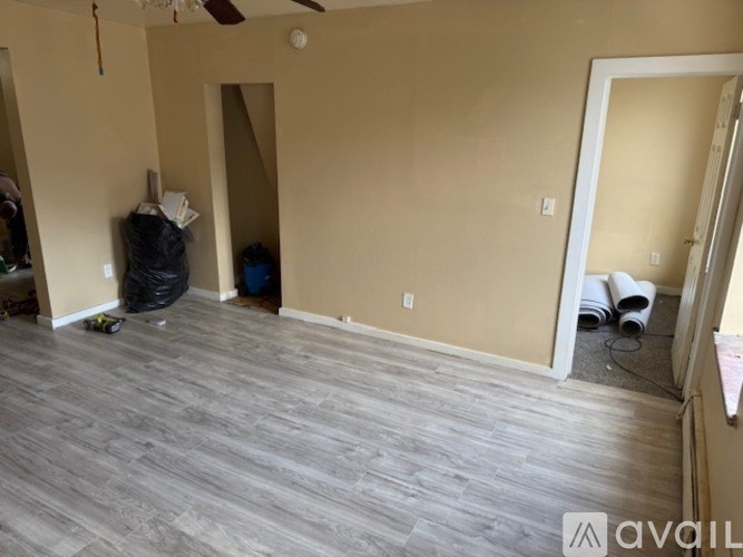 A room with a wooden floor and walls painted in a light color with a ceiling fan.