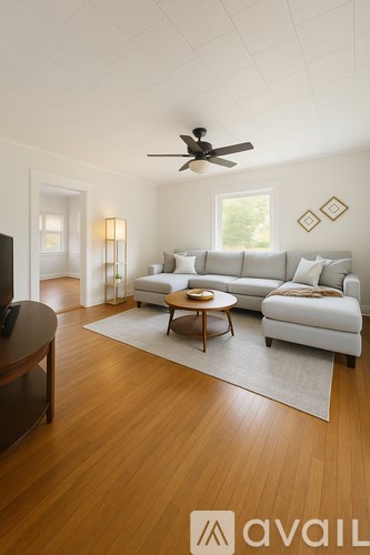 A living room with a white couch, a brown coffee table, and a ceiling fan.