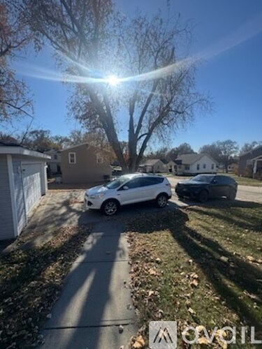A white car is parked on a driveway in front of a house.