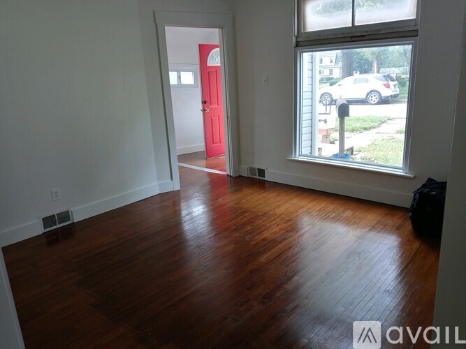 A room with a red door and wooden flooring.