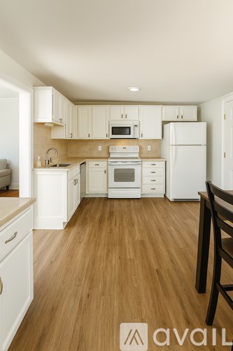 A kitchen with white appliances and wooden floors.
