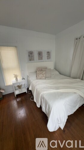 A bedroom with a white bed and a white nightstand with a lamp.