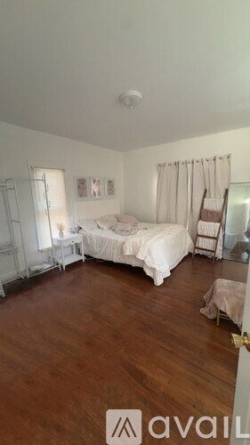 A bedroom with a large bed and wooden floors.