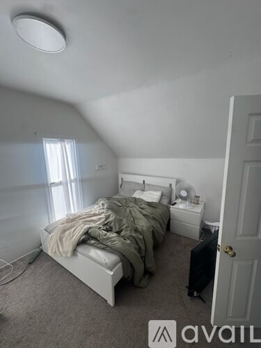 A bedroom with a bed, nightstand, and window.