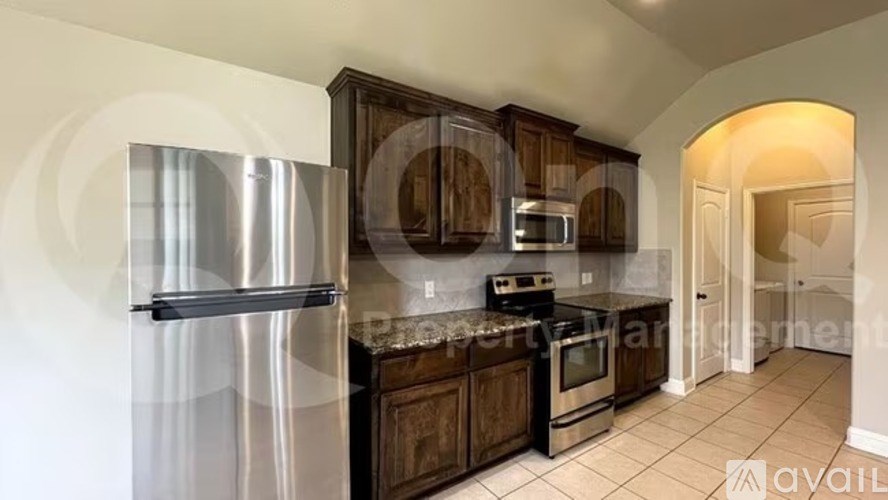 A kitchen with a stainless steel refrigerator and wooden cabinets.
