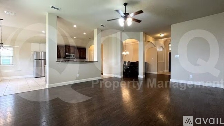 A spacious living room with a ceiling fan and hardwood flooring.