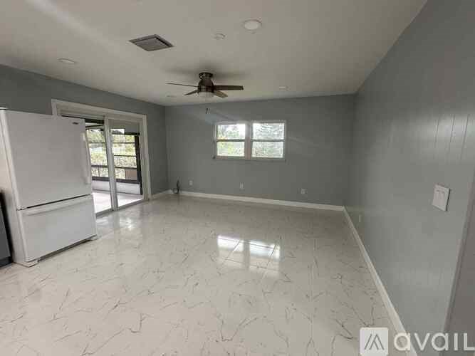A spacious room with a white floor and ceiling fan.
