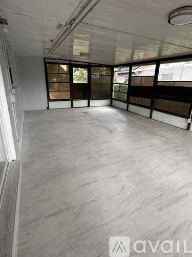 A large empty room with a grey floor and white walls.