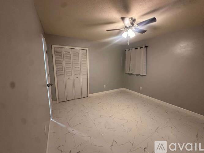 A room with a ceiling fan and a marble floor.