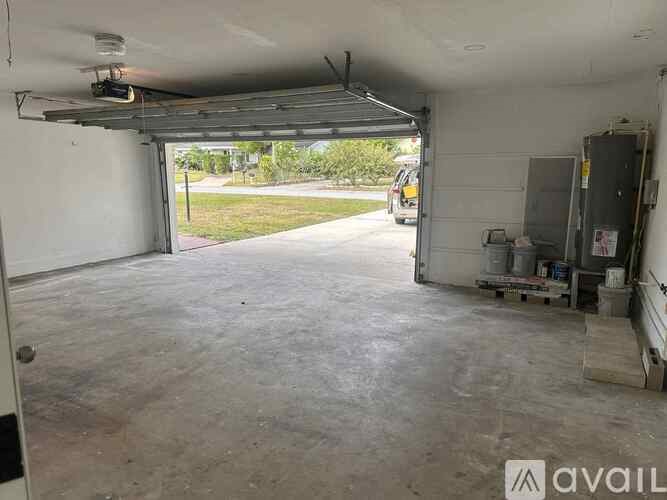 A large garage with a white wall and a door open to the outside.