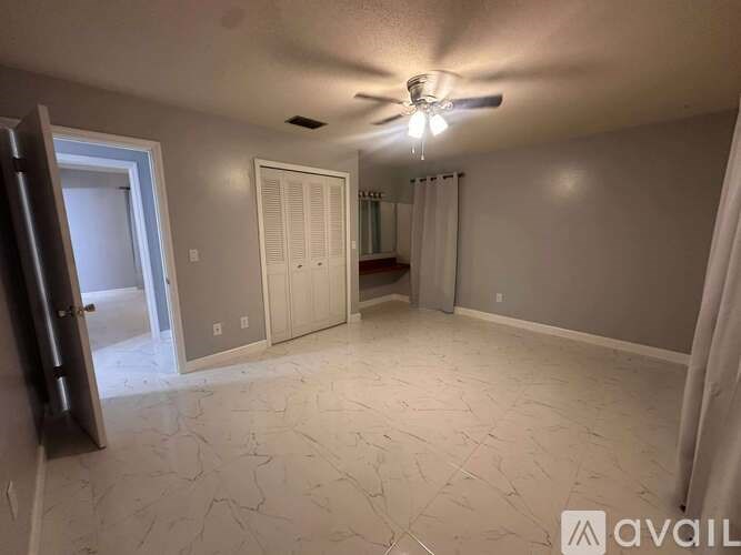 A room with a ceiling fan and a door.